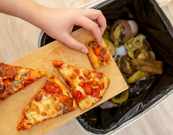 Person putting pizza slices into bin
