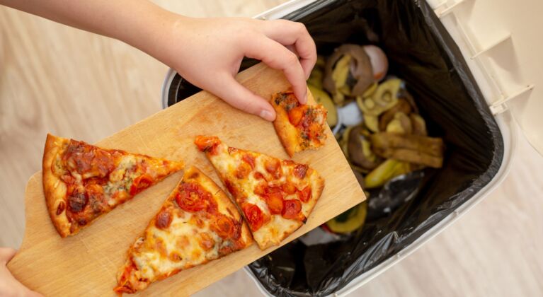 Person putting pizza slices into bin